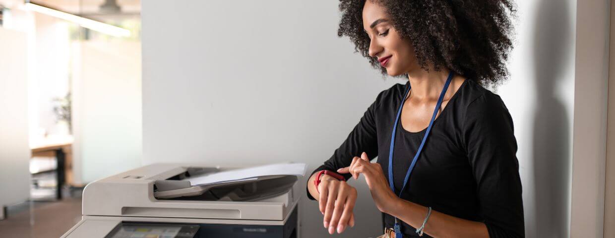 woman looking at watch next to printer